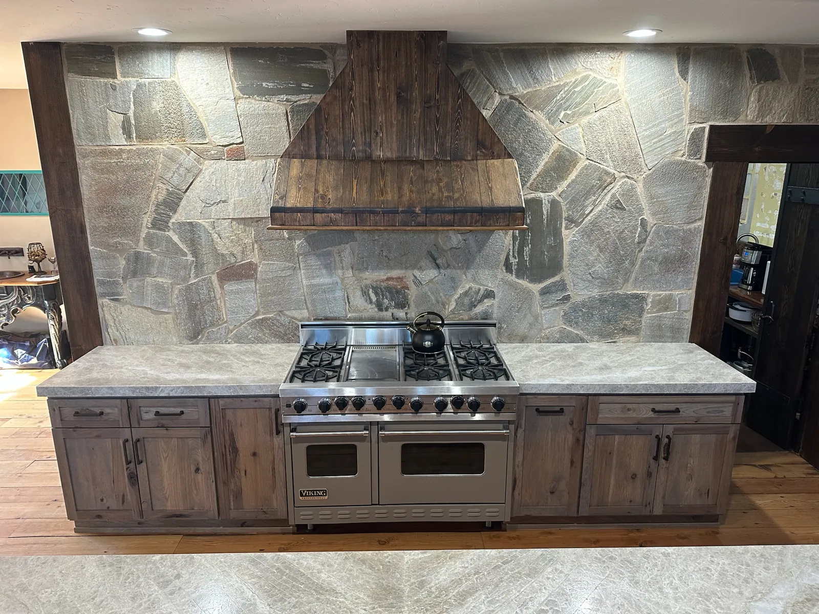 Taj Mahal quartzite countertops with a laminated beveled edge flanking a range under a stacked stone wall in Gardnerville