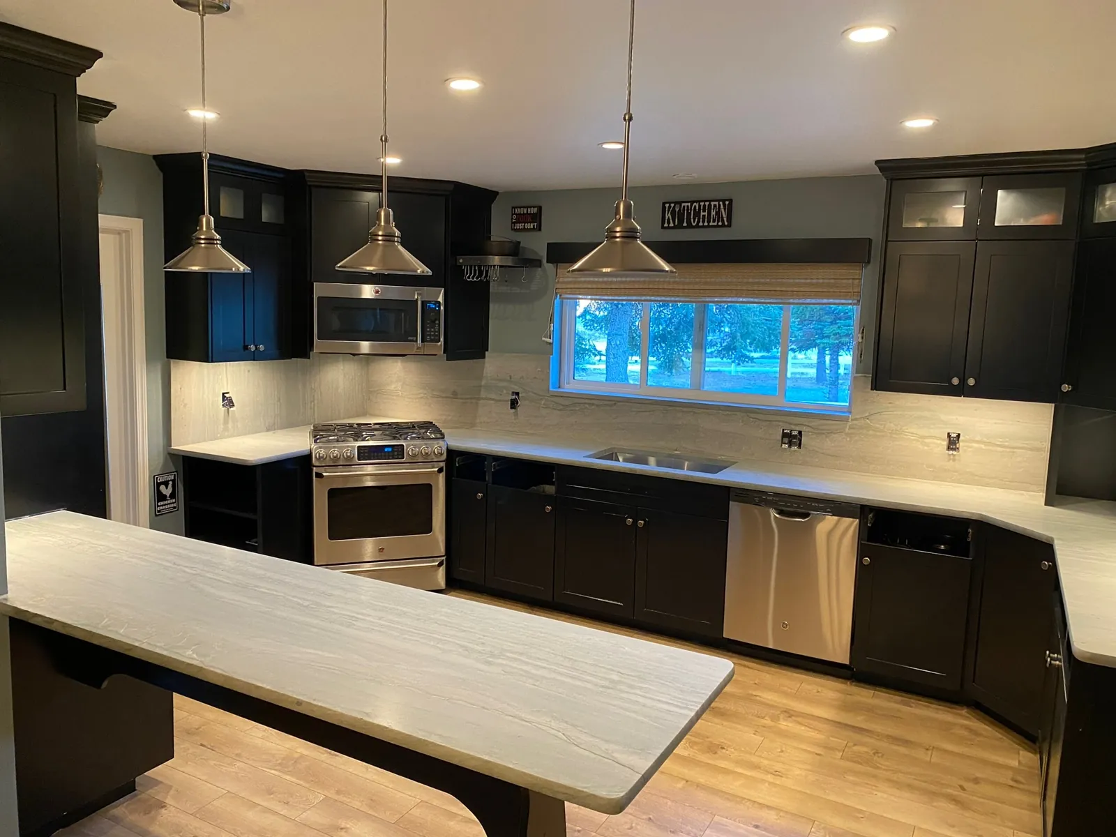 Satin quartzite countertops with a crescent edge and full-height backsplash in a Washoe Valley kitchen with dark cabinets